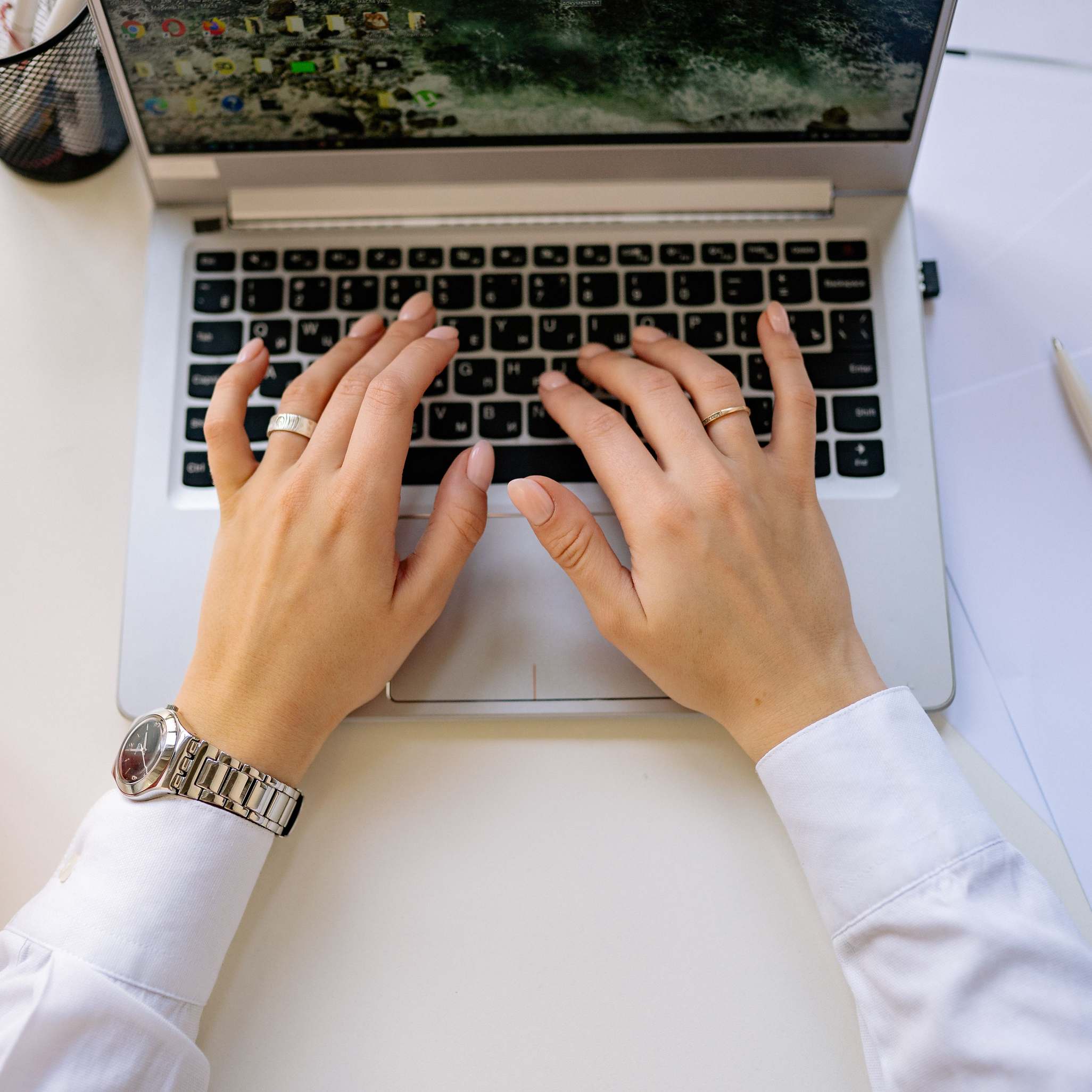 Hands typing on a laptop keyboard in a bright modern workspace